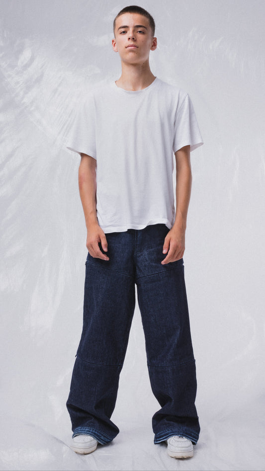 Modello con jeans modulari MO Interchangeable in denim scuro e t-shirt bianca su sfondo neutro