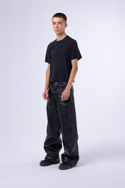 Modello con pantaloni modulari MO Interchangeable in denim nero, maglietta nera, sfondo neutro