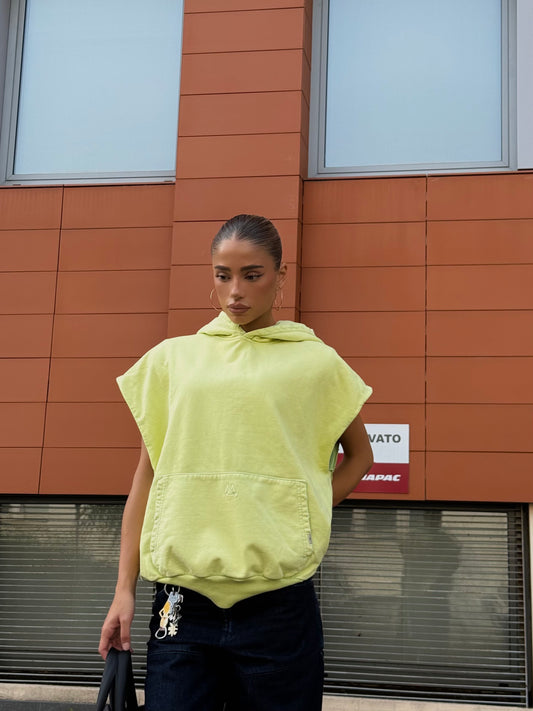 Donna con smanicato giallo lime MO Interchangeable e jeans modulari davanti a edificio moderno.